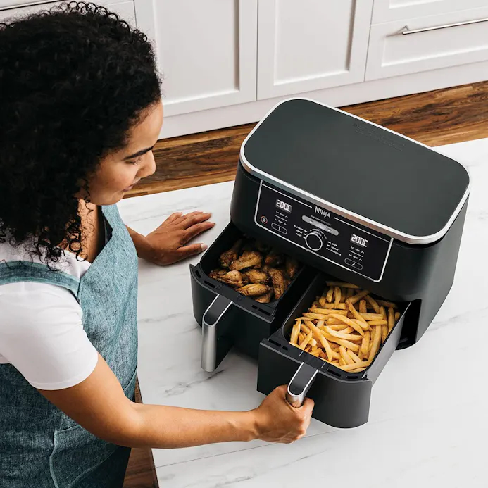 Vrouw doet kip en patat in airfryer