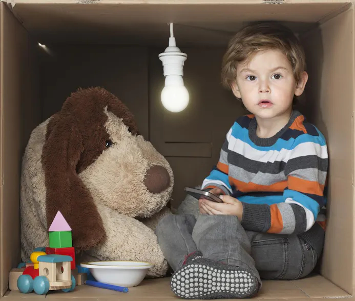 Jongen en speelgoedknuffel in kartonnen doos