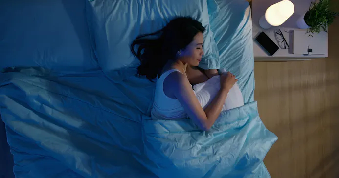 Slapende vrouw met smartphone op het nachtkastje