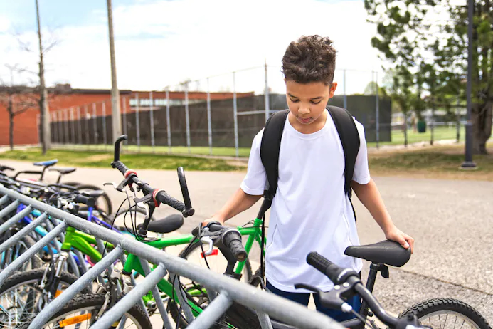 Kind dat zijn fiets in een fietsenrek zet bij school