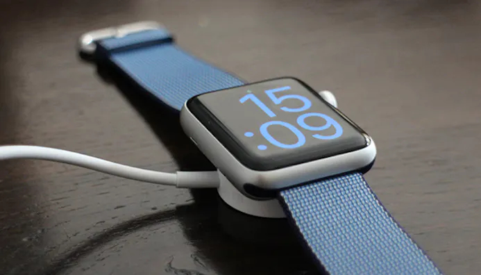 Je laadt de Apple Watch op met een magnetische plateautje.