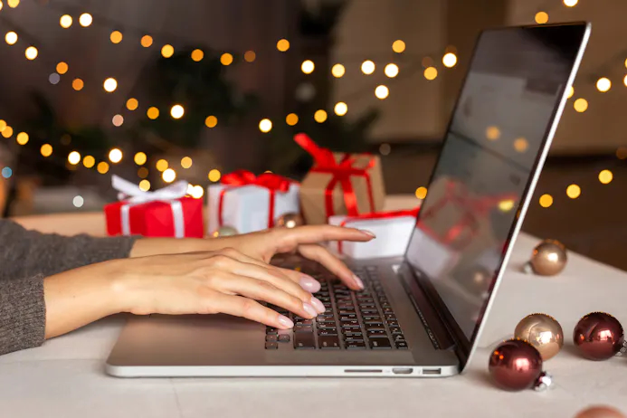 vrouw achter laptop en kerstcadeaus op de achtergrond