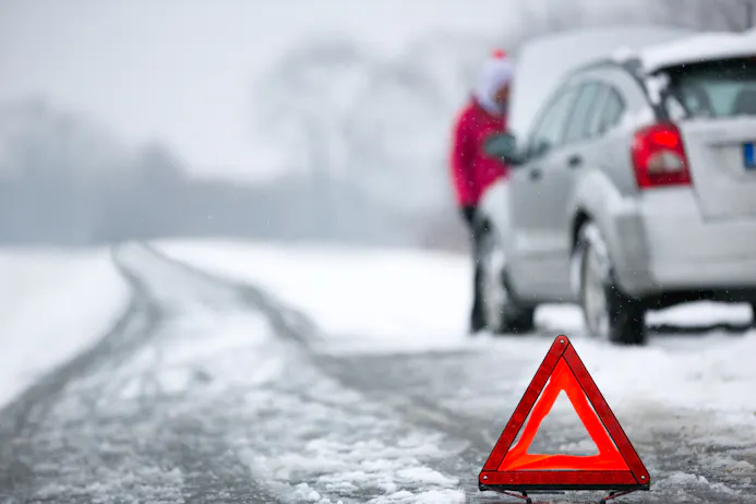 Auto op besneeuwde weg met uitgeklapte gevarendriehoek