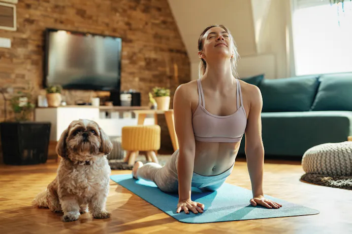 Vrouw in yoga-cobrahouding, met hond