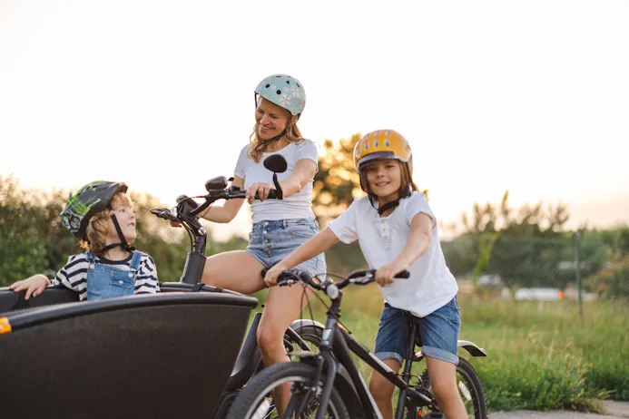 Moeder met kinderen op fiets en bakfiets met helmen