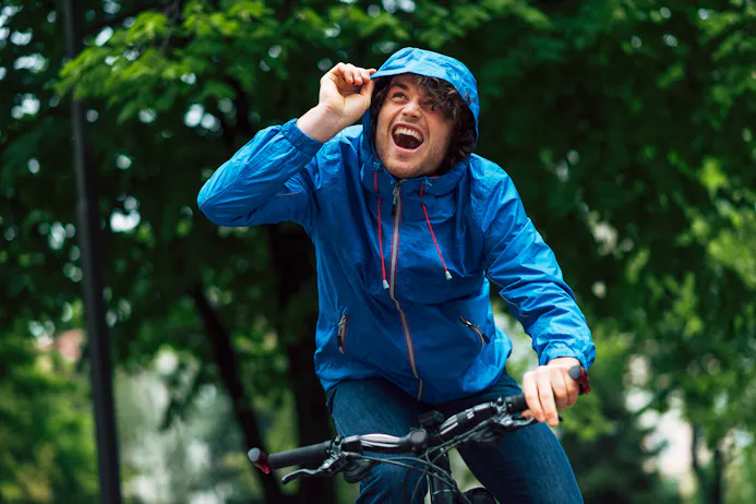 Man met blauwe regenjas op fiets