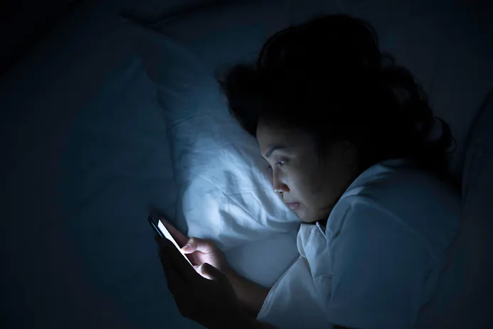 Vrouw in bed kijkt op smartphone