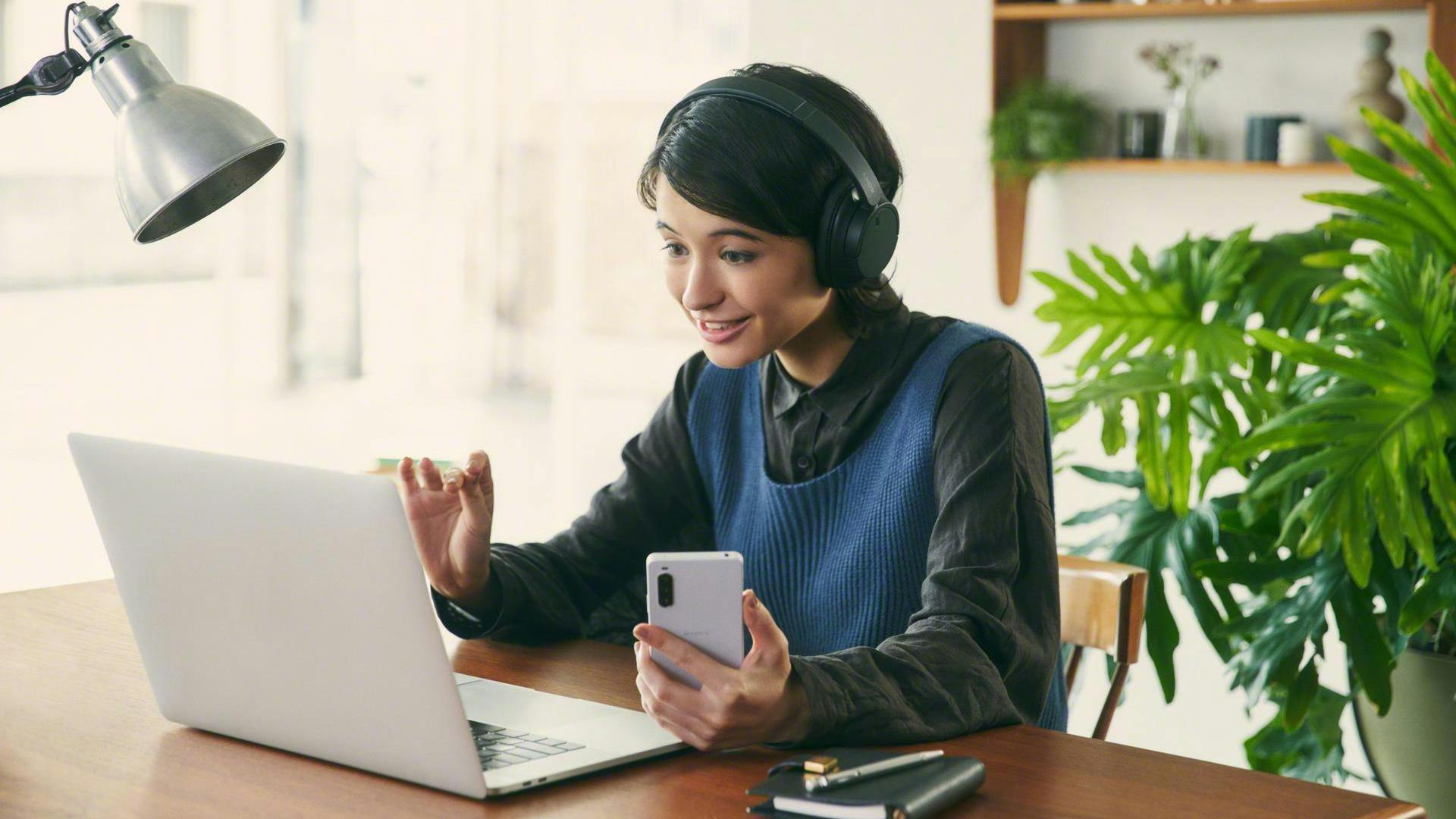 Vrouw met hoofdtelefoon woont een videomeeting via de laptop bij.