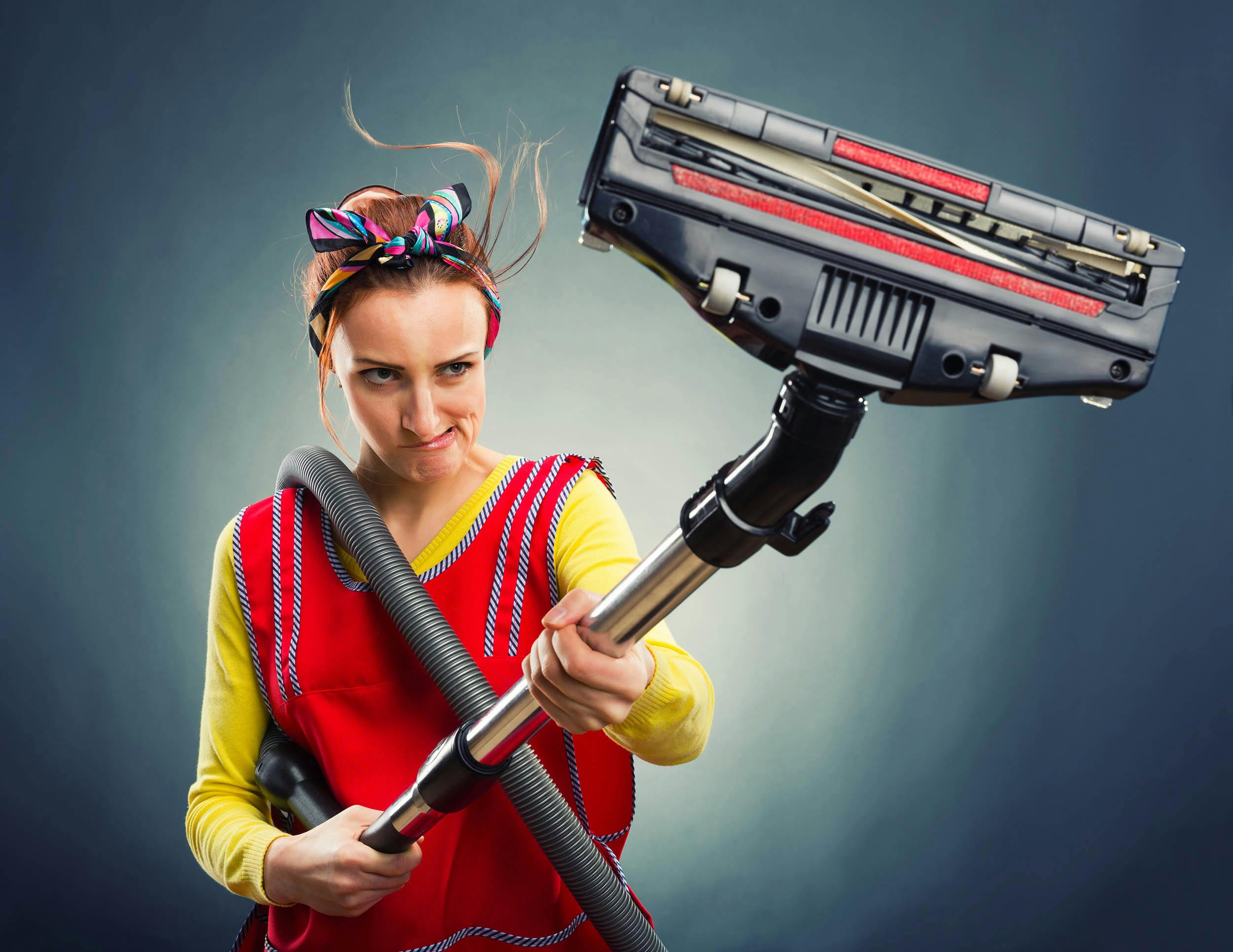 Huisvrouw die boos naar haar stofzuiger kijkt