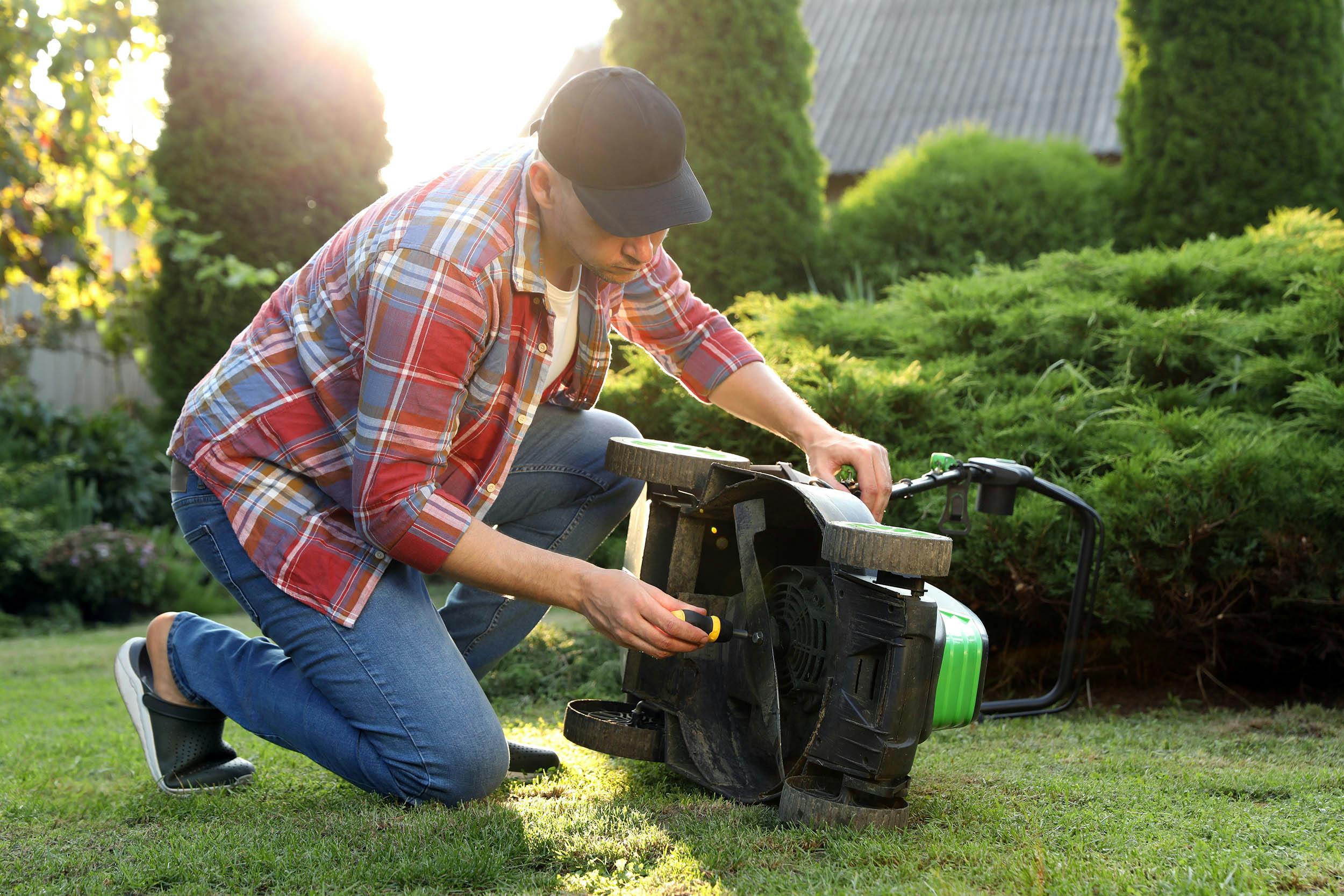 Man die sleutelt aan grasmaaier